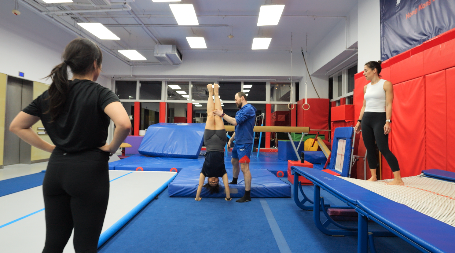 Adult gymnast performing a spotted handstand at ProGym Wan Chai