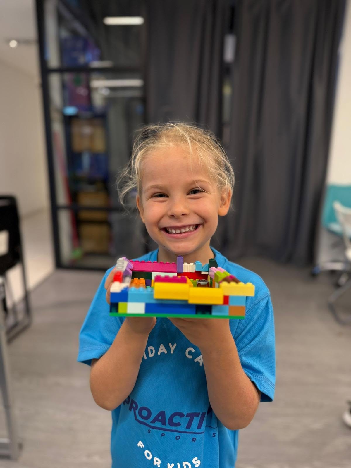 Young camper proudly holding up a Lego build during camp downtime