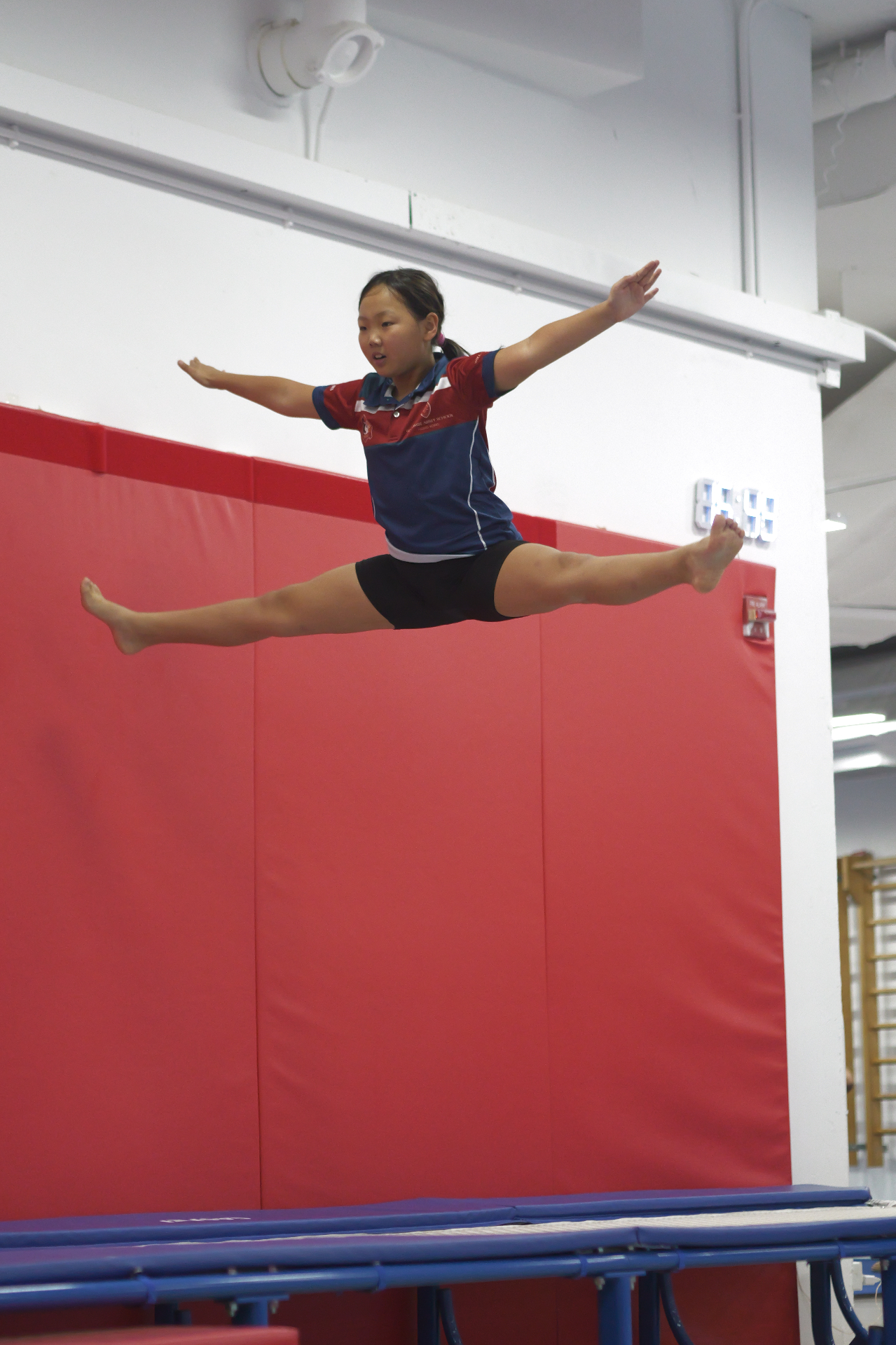 Recreational gymnast performing split leap on trampoline