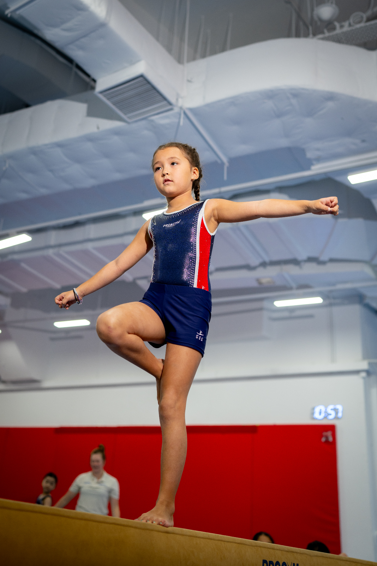 Young gymnast in a ProActiv leotard balancing on the beam at a Hong Kong Gymnastics Camp