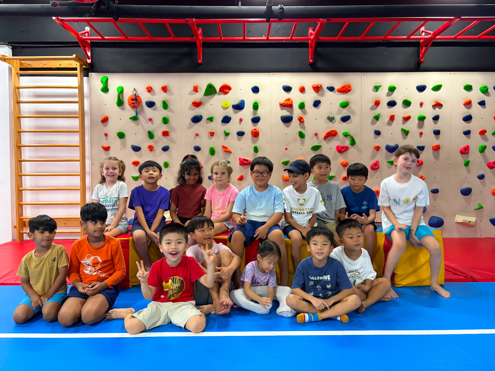 Group of campers in front of the climbing wall at Prodigy Katong Point