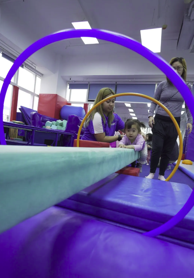Mini-Camp toddler balancing through hoops with coach support at ProActiv Hong Kong