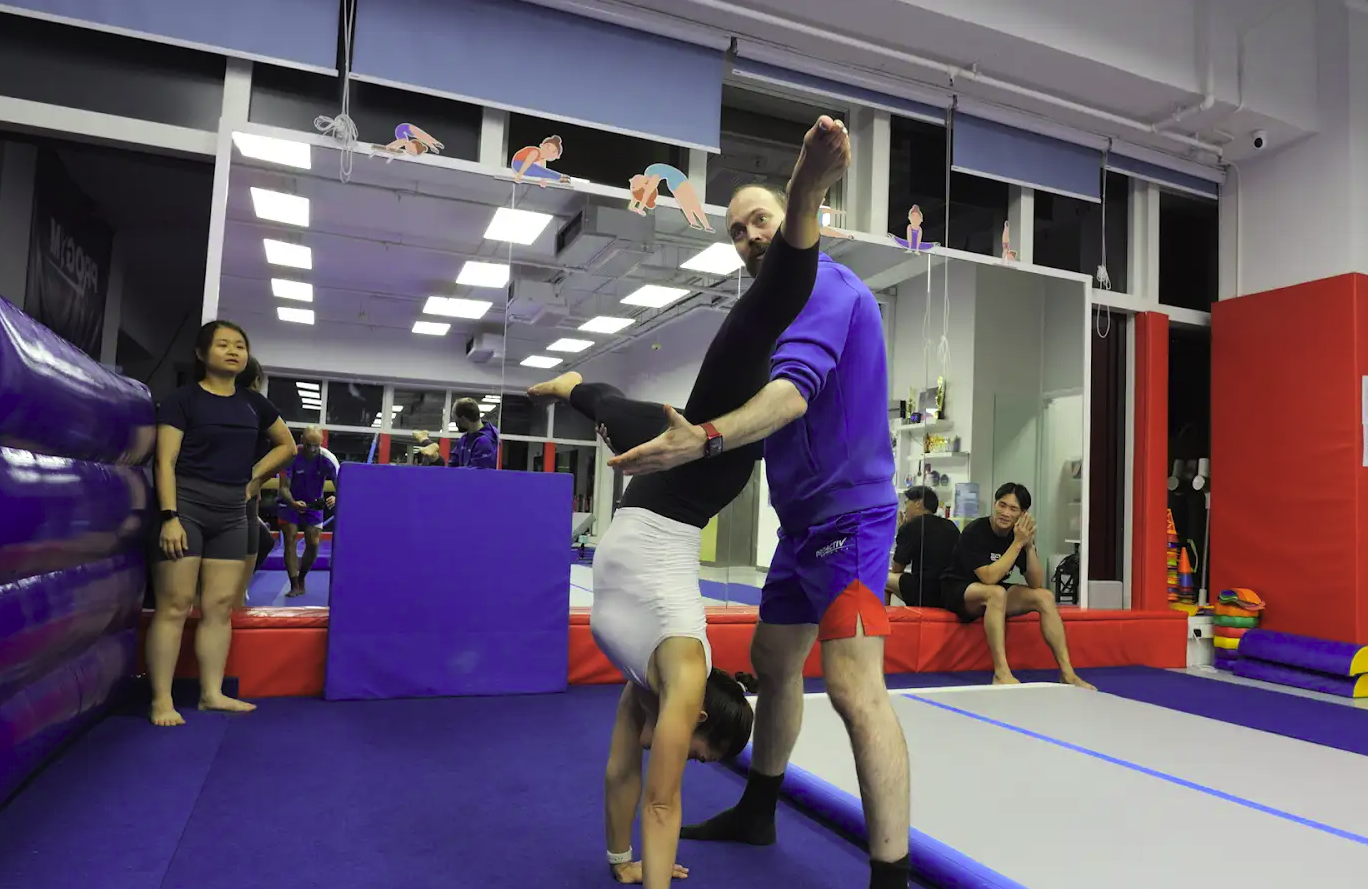 Coach assisting adult student with handstand technique