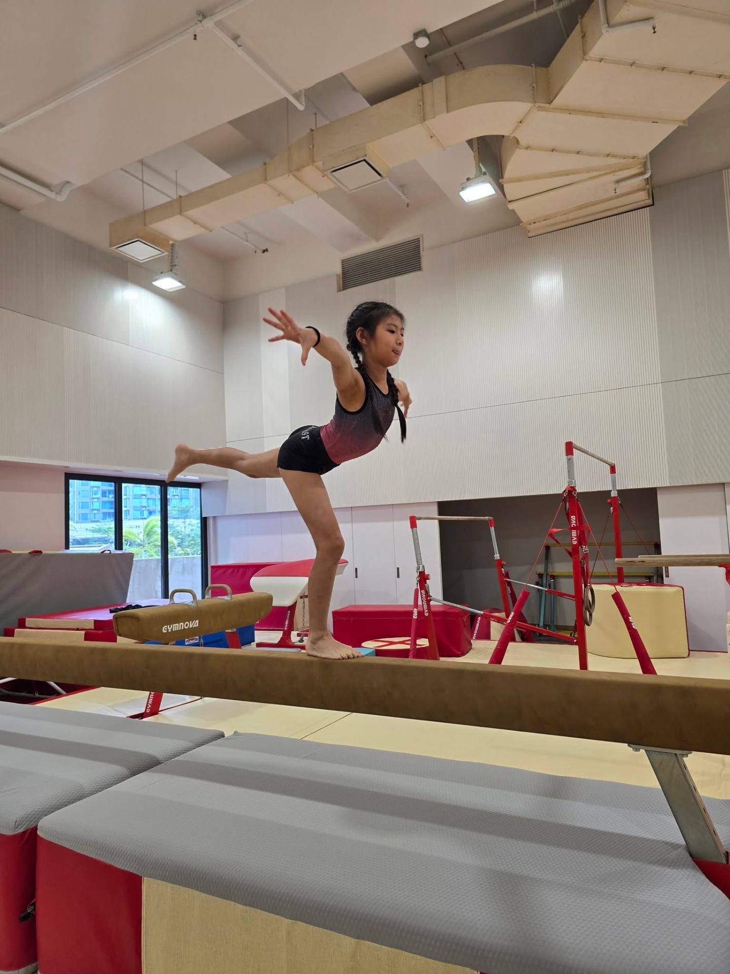Young gymnast holding an arabesque on the balance beam at a ProActiv Hong Kong Gymnastics Camp