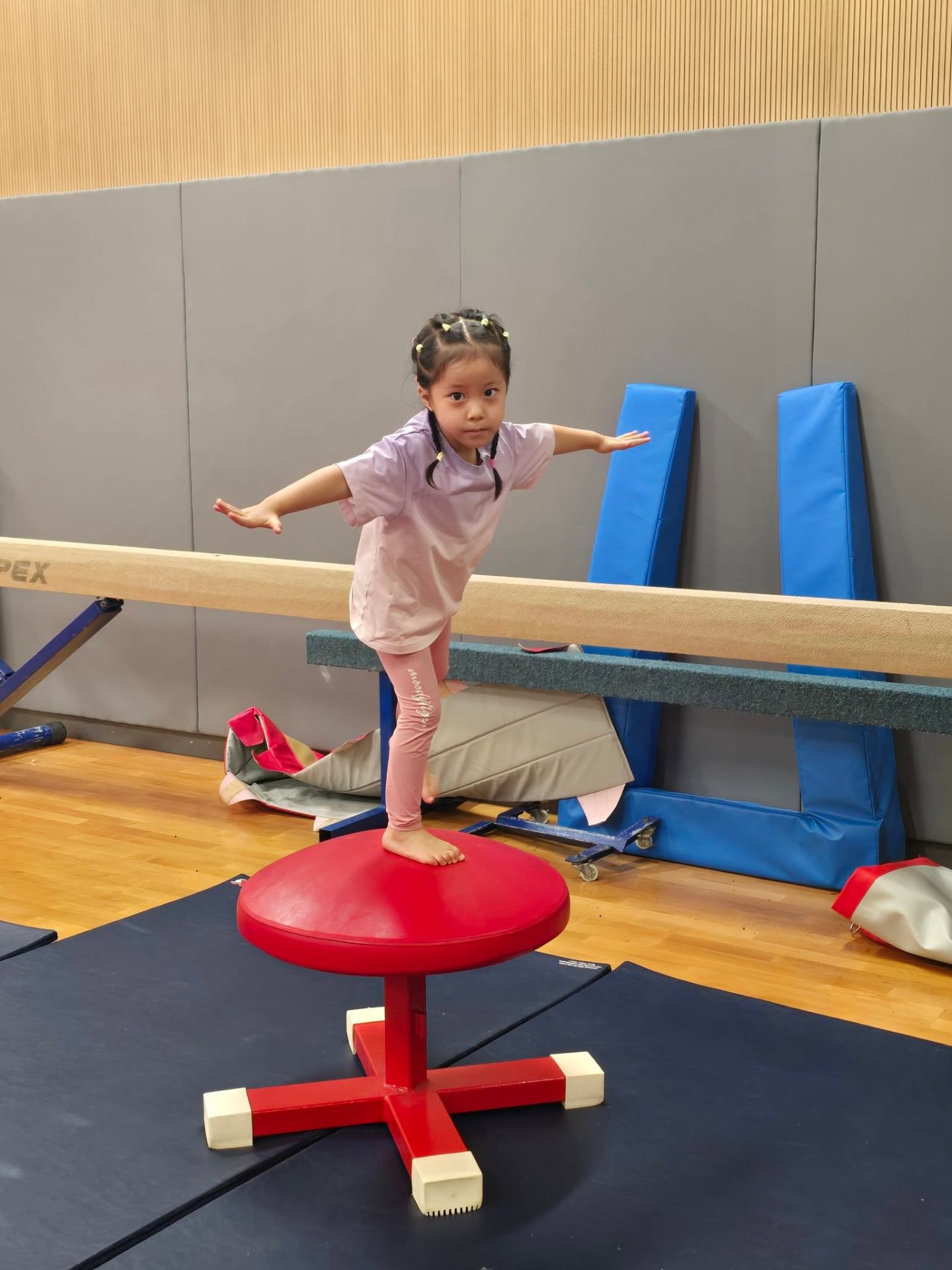 Young gymnast balancing on a podium beside the beam at a ProActiv Hong Kong Gymnastics Camp