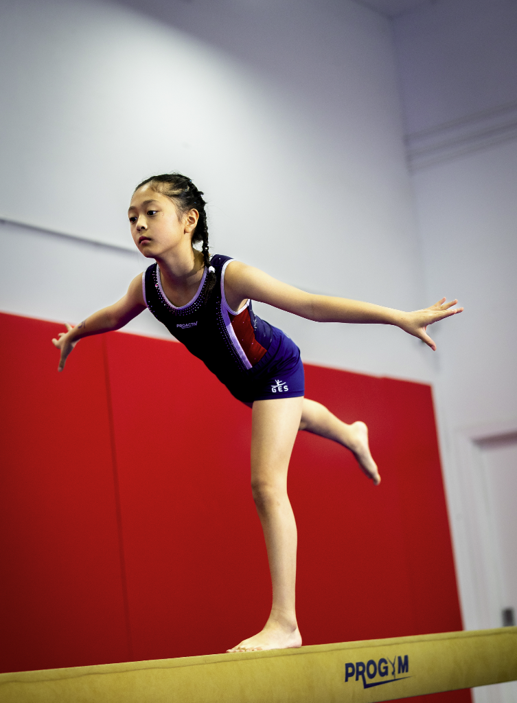 Gymnast balancing on beam at ProGym in competition leotard