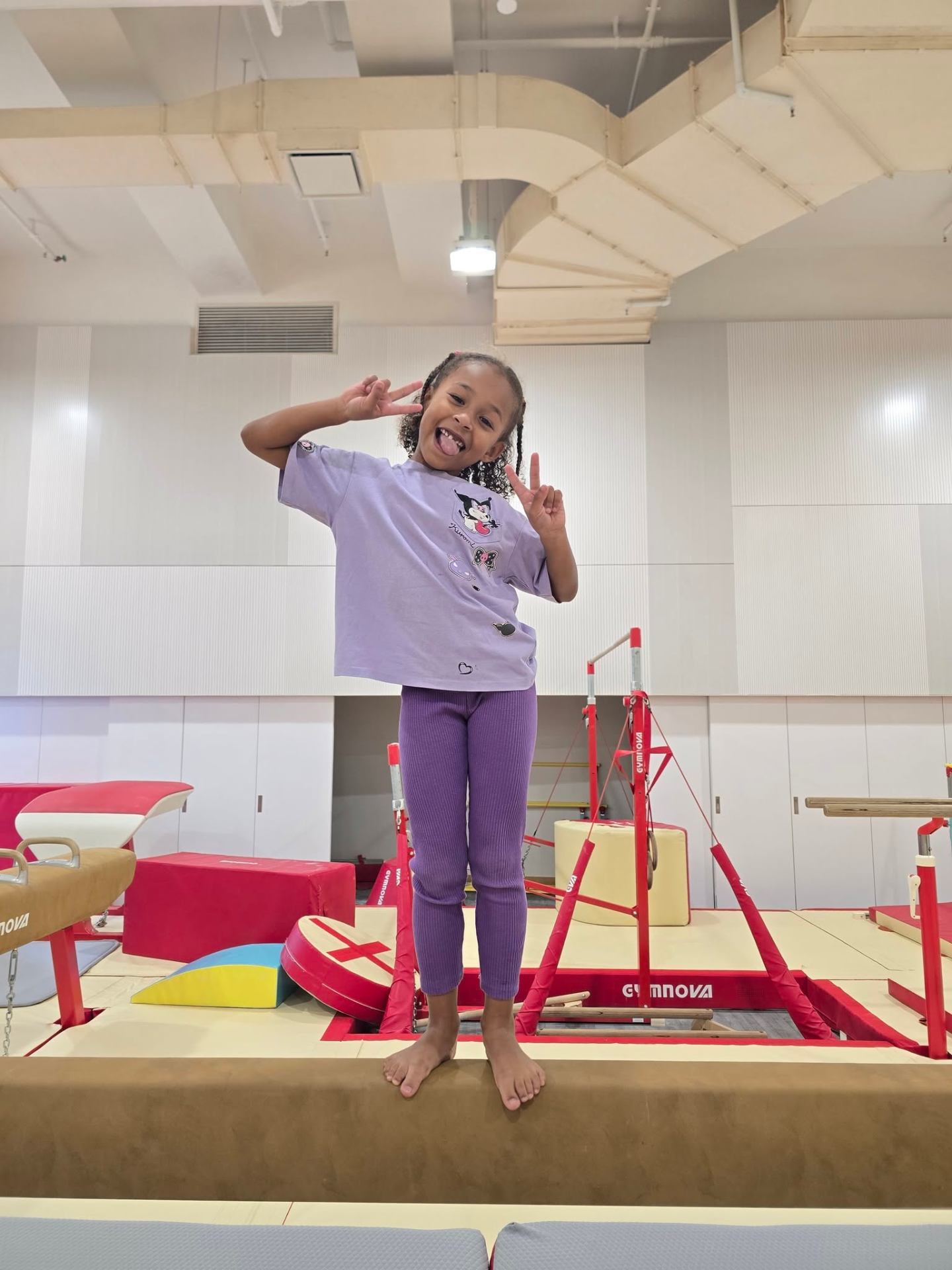 Smiling child posing on the balance beam at a ProActiv Hong Kong Gymnastics Camp