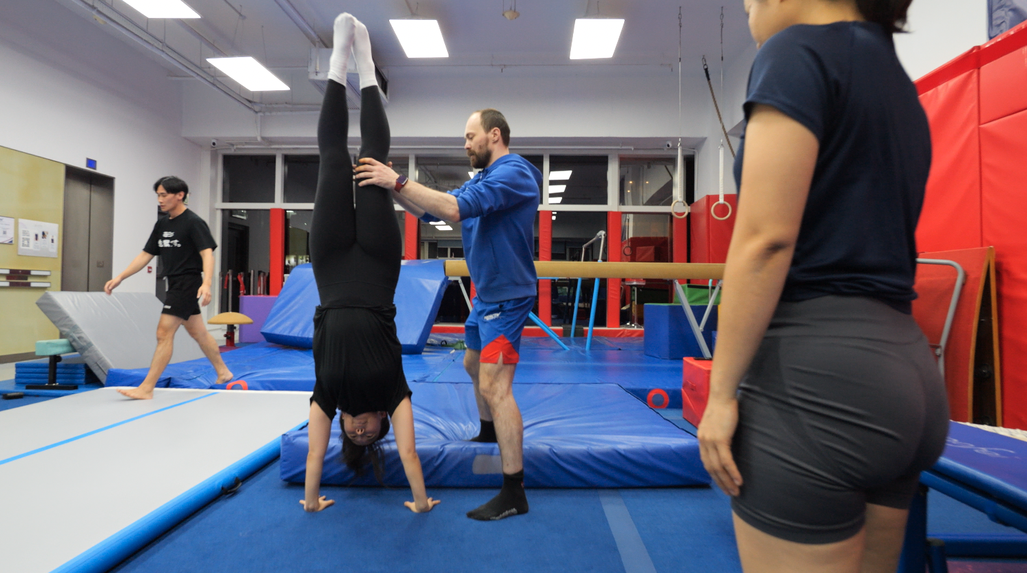 Adult gymnast practising a handstand with coach support at ProGym