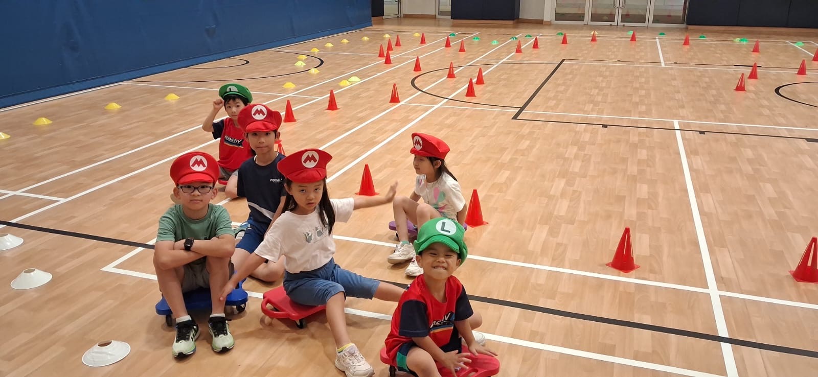 Children in Mario-themed hats sitting on scooters at a ProActiv Hong Kong Multi-Activity Camp