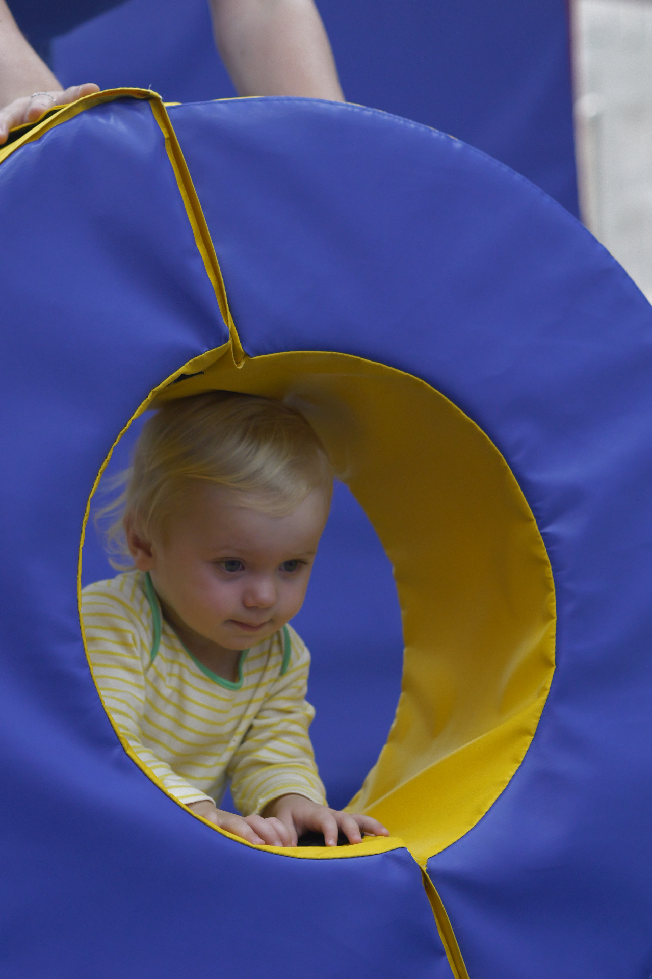 Toddler crawling through a soft-play tunnel at ProGym