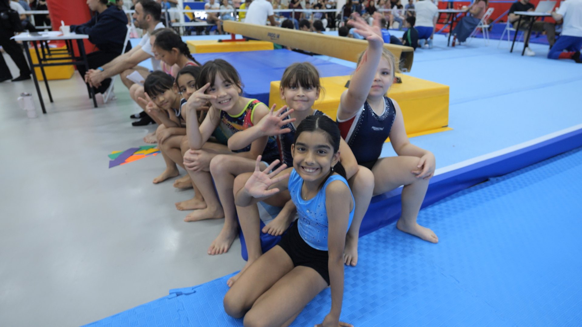 Gymnasts waving and cheering together at a ProActiv Sports gymnastics event