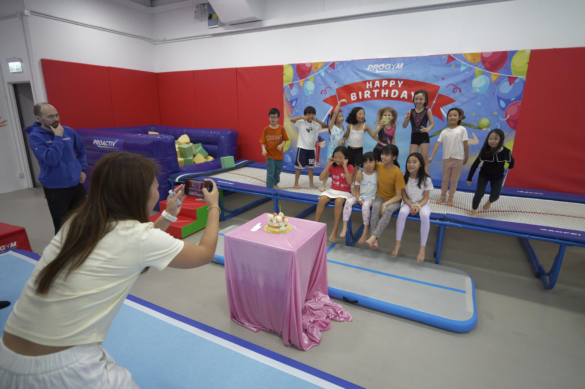 Birthday party guests posing around the cake at a ProGym Hong Kong celebration